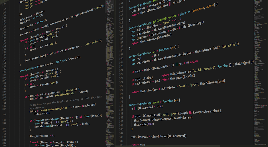 A person working on a laptop, viewing a screen filled with lines of code and programming text. The individual has neatly manicured nails and is seated at a white desk against a wooden background. The